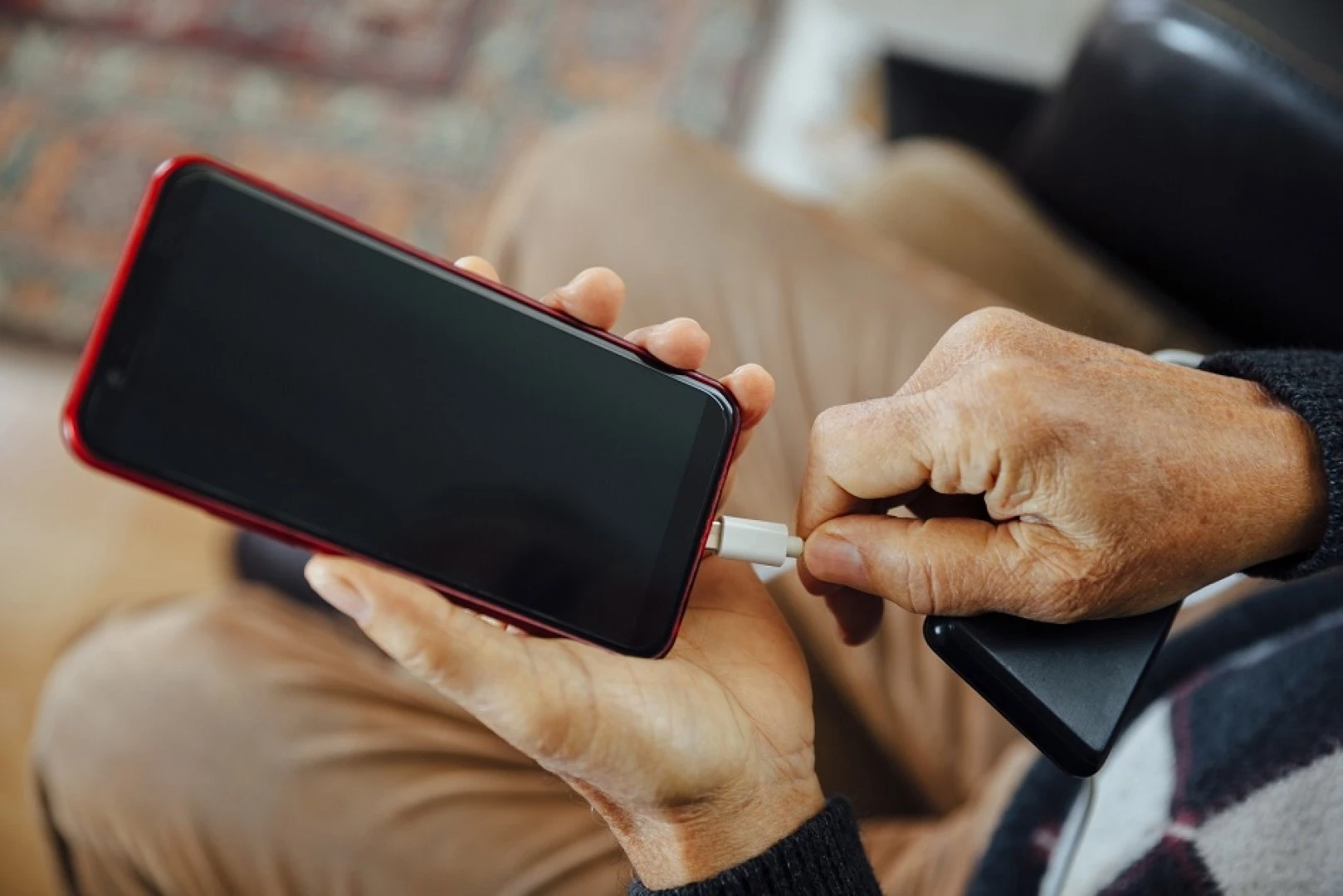 Senior man charging his phone, charging stations supplied by GOLDEN AGE HOUSING PRODUCTS