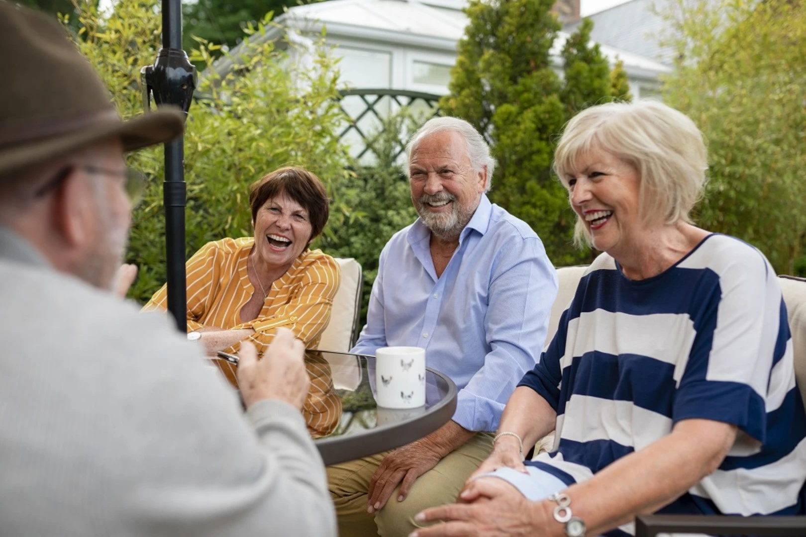 Elderly people sitting outside and talking, seated on the outdoor chairs by a outdoor table supplied by GOLDEN AGE HOUSING PRODUCTS